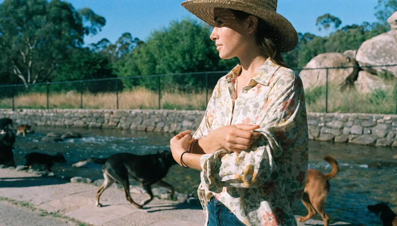 Woman adjusting sleeve by park stream.